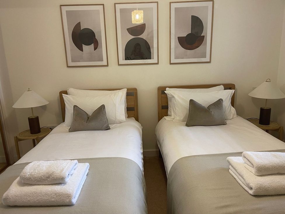 A bedroom with two single beds and artwork on the wall at Anchors Rest in St. Ives
