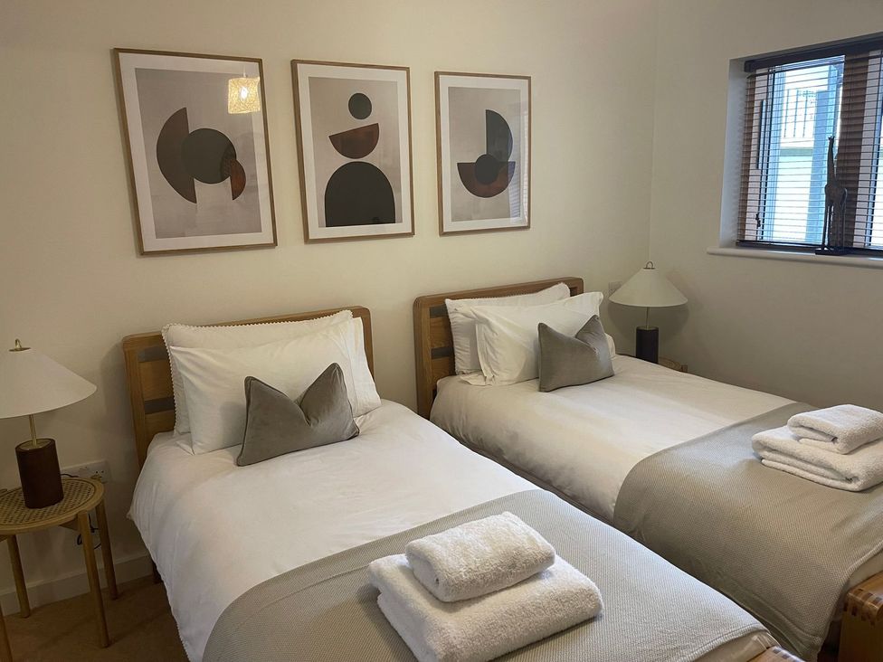 A bedroom with twin beds and wall art at Anchors Rest in St. Ives