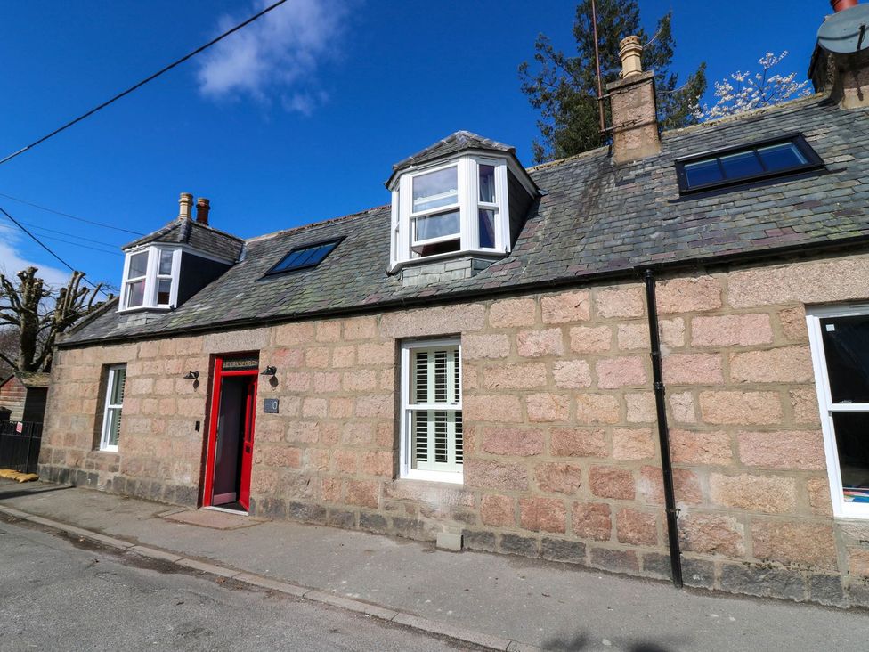A house with a red door and multiple windows at Evansford in Ballater