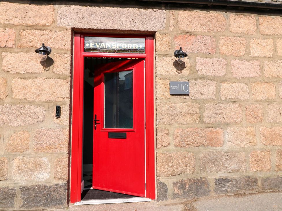 An entrance with a red door and stone wall at Evansford in Ballater