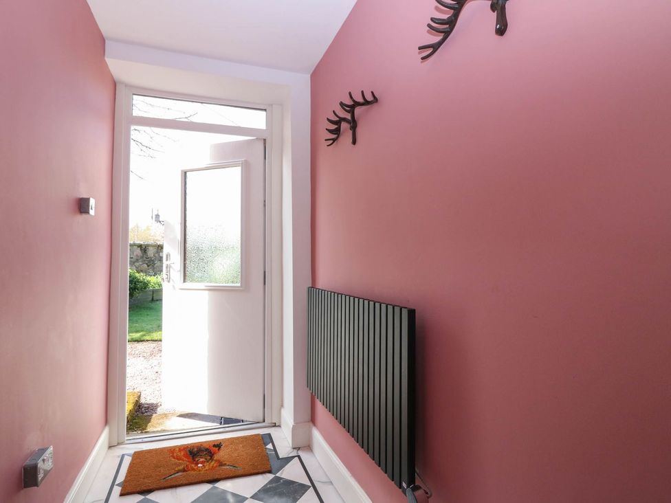 A hallway with a front door and radiator at Evansford in Ballater