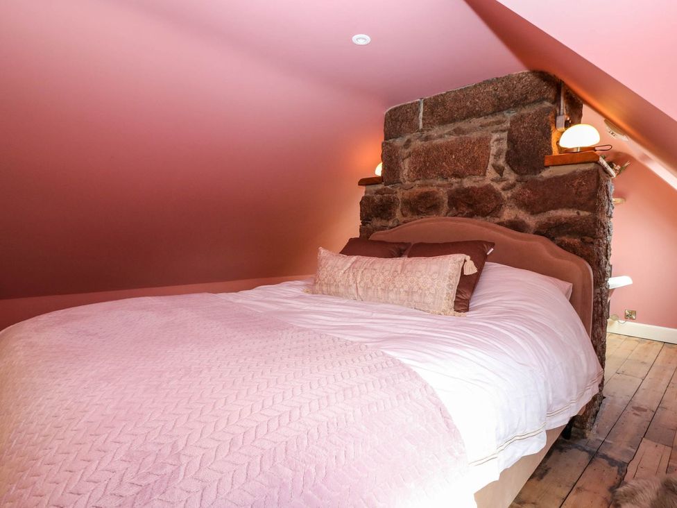 A bedroom with a bed against a stone wall at Evansford in Ballater