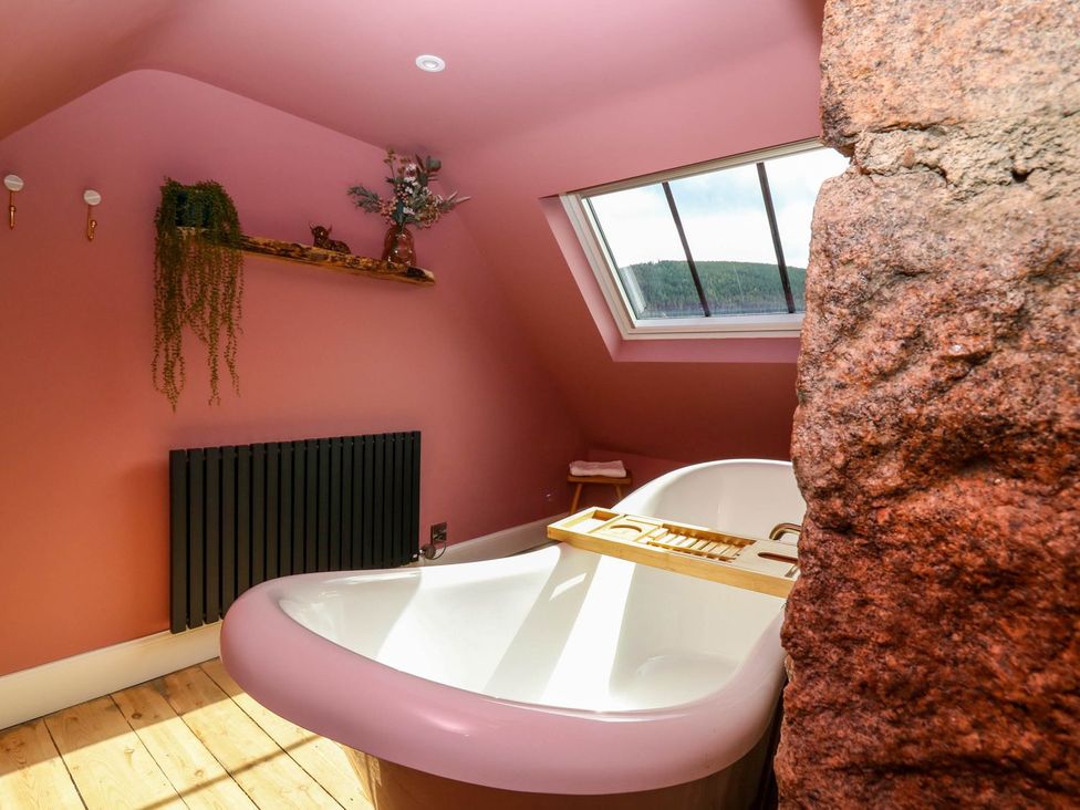 A bathroom with a bathtub and a shelf at Evansford in Ballater