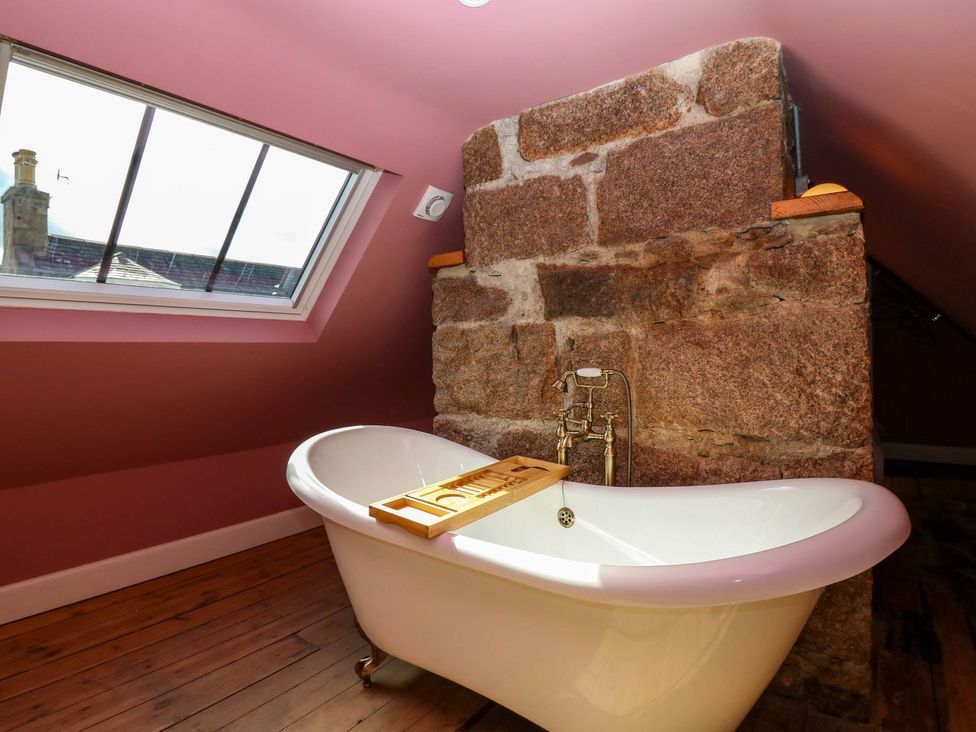 A bathroom with a bathtub and stone wall at Evansford in Ballater