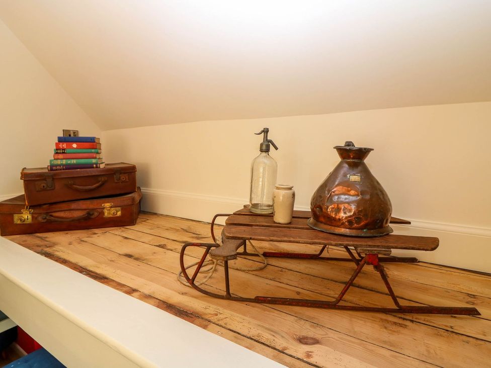 A collection of items including books, a suitcase, and a sled in the attic at Evansford in Ballater