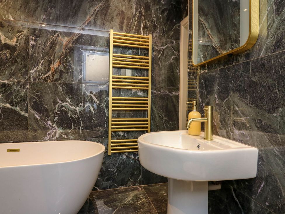 A bathroom with a bathtub, sink, and towel radiator at Evansford in Ballater