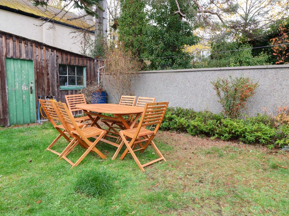 A garden with a wooden table and chairs at Evansford in Ballater