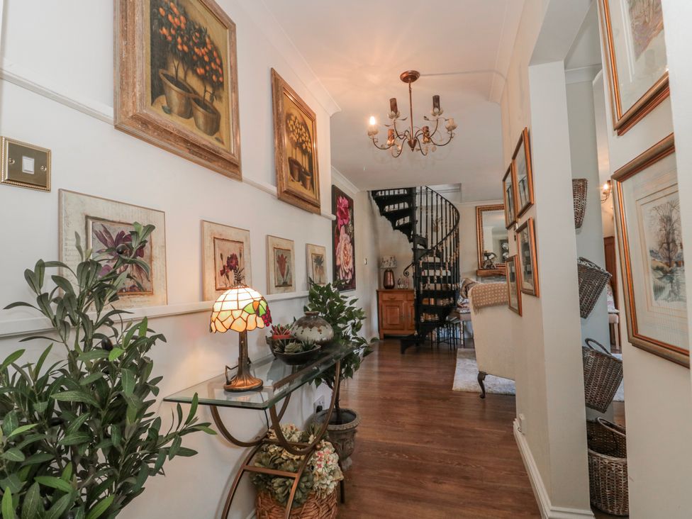 A hallway with paintings on the wall and a staircase at 7 The Cedars Wotton-Under-Edge