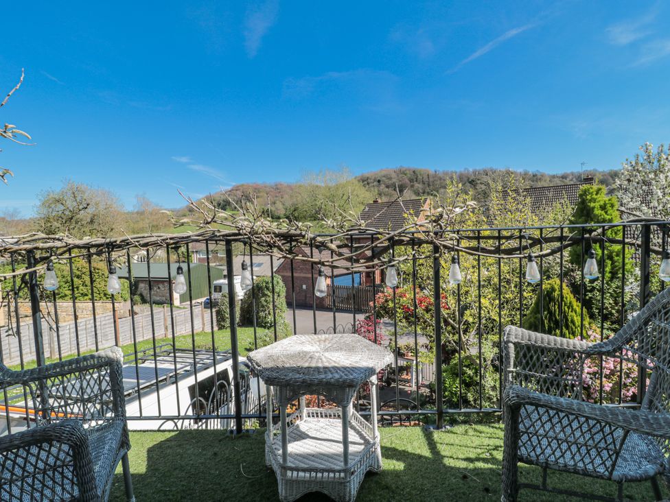 A balcony with chairs and a table overlooking a garden at 7 The Cedars Wotton-Under-Edge