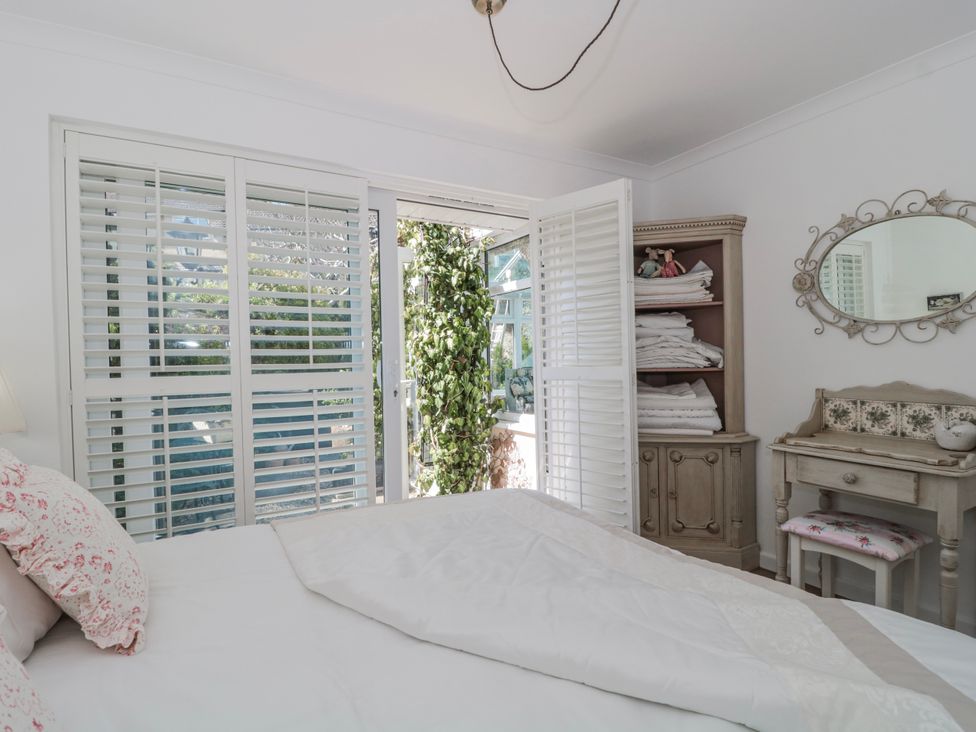A bedroom with a bed and window opening to a garden at 7 The Cedars Wotton-Under-Edge