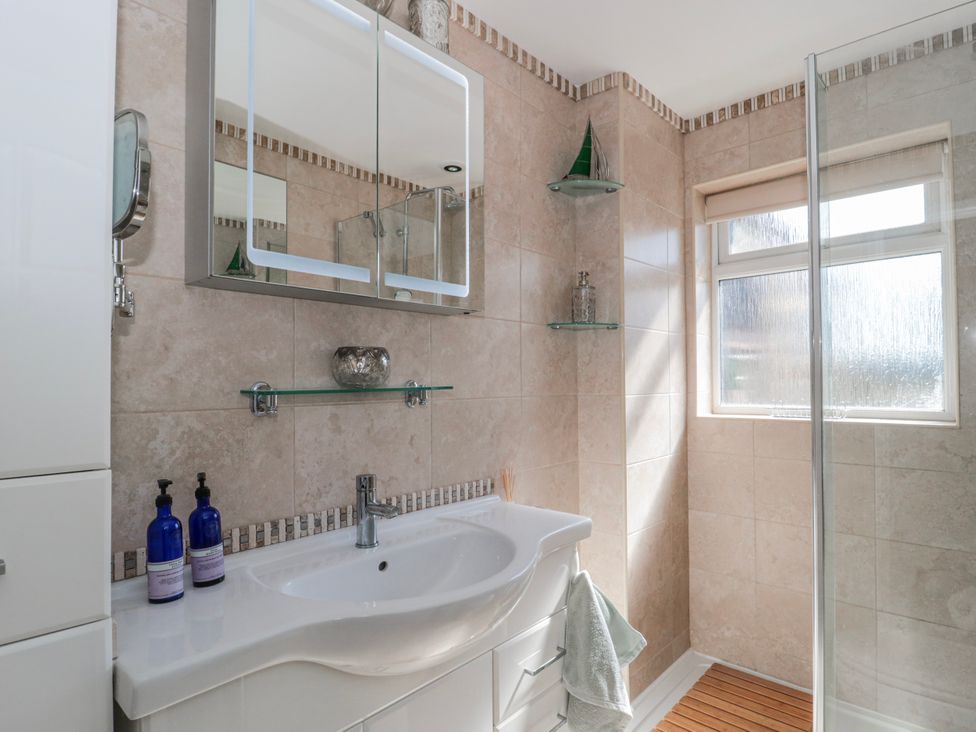 A bathroom featuring a sink, mirror, shower, and window at 7 The Cedars in Wotton-Under-Edge