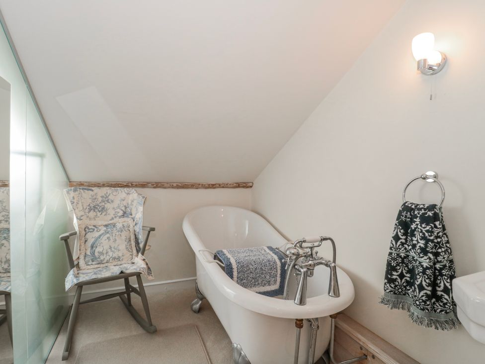 A bathroom with a bathtub, chair and towel rack at 7 The Cedars Wotton-Under-Edge