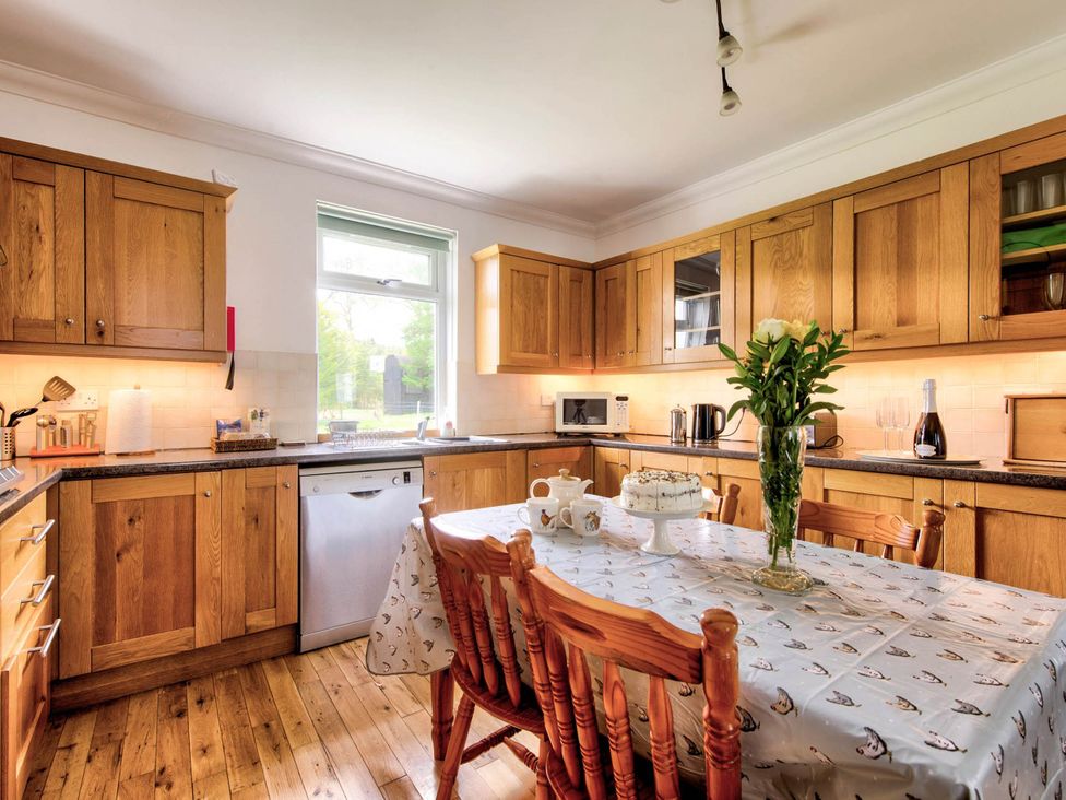 A kitchen with wooden cabinets and a table set at Argyll Farmhouse-Idyllic Setting-Sleeps10 in Dunoon