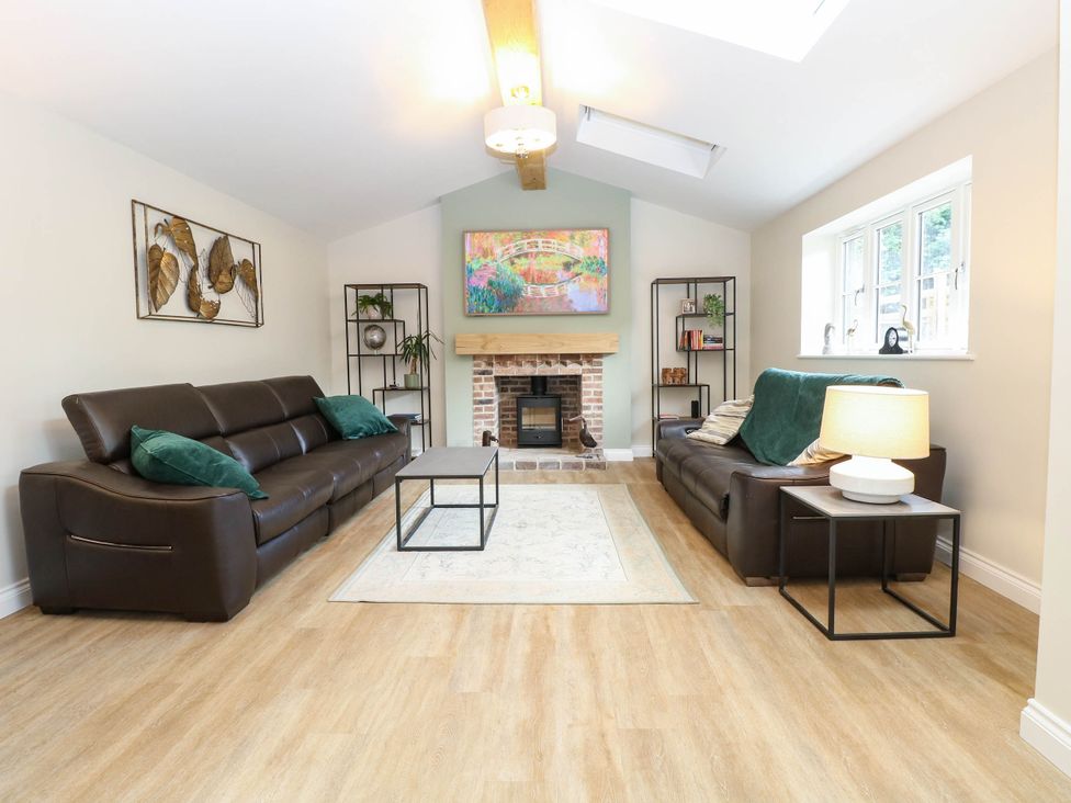 A living room with sofas and a fireplace at Bramley Cottage in Worlingham