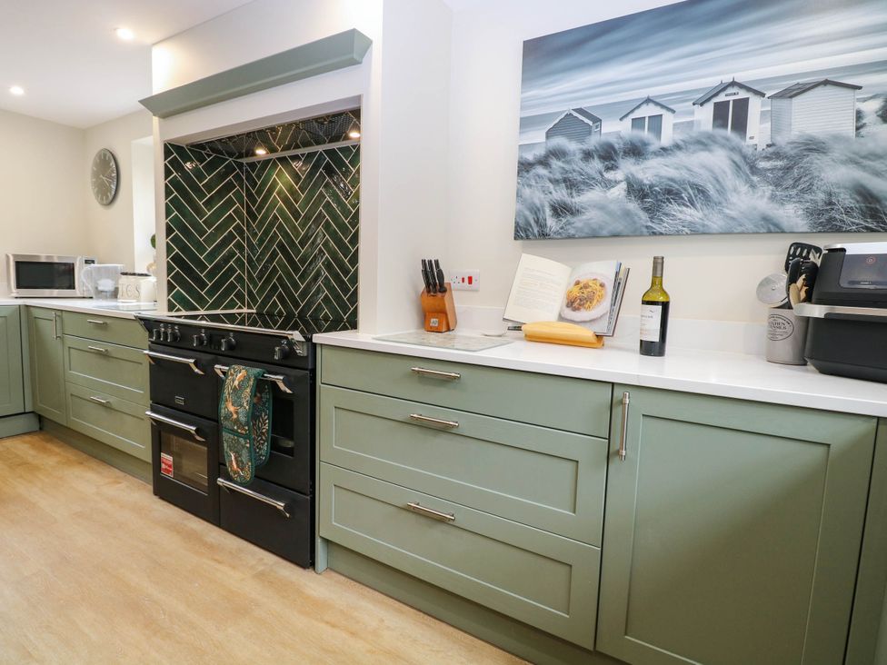 A kitchen with cabinets stove and utensils at Bramley Cottage in Worlingham