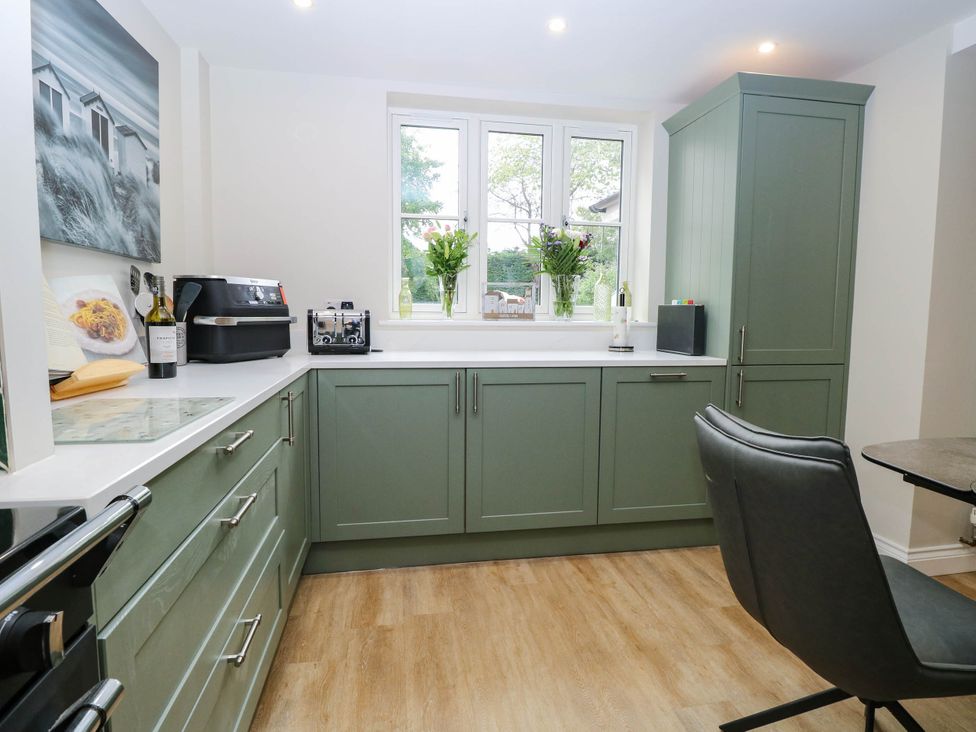 A kitchen with green cabinets and a window at Bramley Cottage in Worlingham