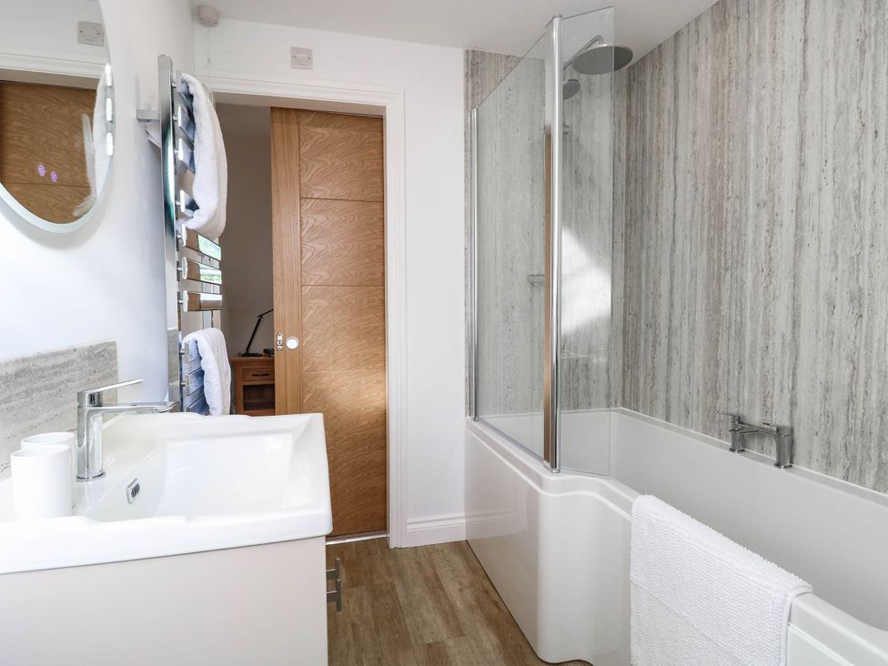 A bathroom featuring a bathtub, sink, and mirror at Bramley Cottage in Worlingham