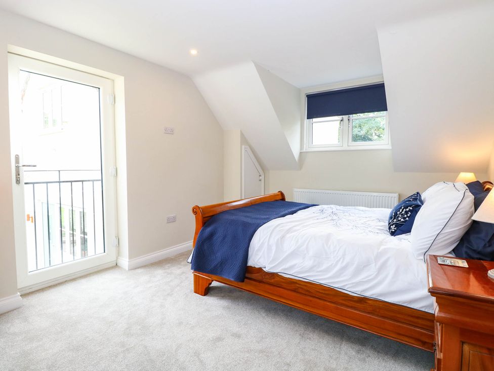 A bedroom with a bed and a door leading to a balcony at Bramley Cottage in Worlingham