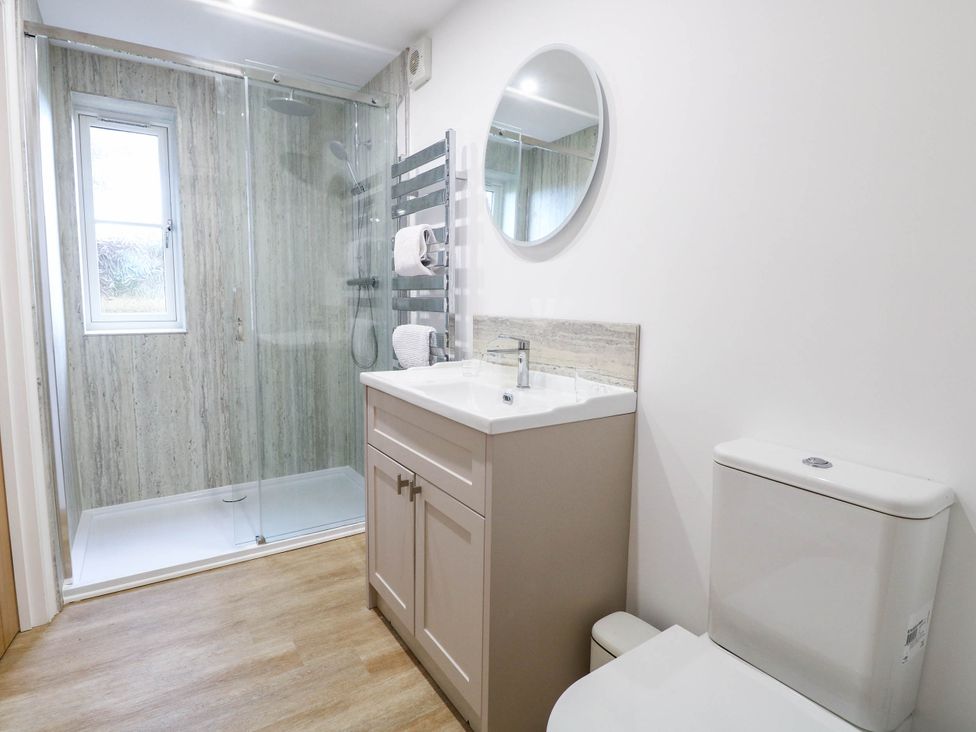 A bathroom with a shower, sink, toilet, and towel rack at Bramley Cottage in Worlingham