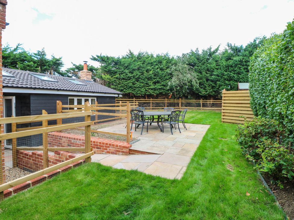 A garden with a patio and table at Bramley Cottage in Worlingham