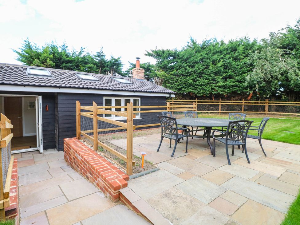 A garden with table and chairs near a house at Bramley Cottage in Worlingham