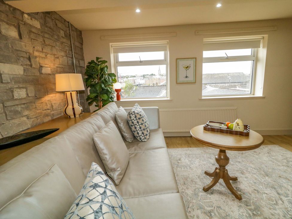 A living room with a sofa, table, and lamp at Apartment 1 in Londonderry