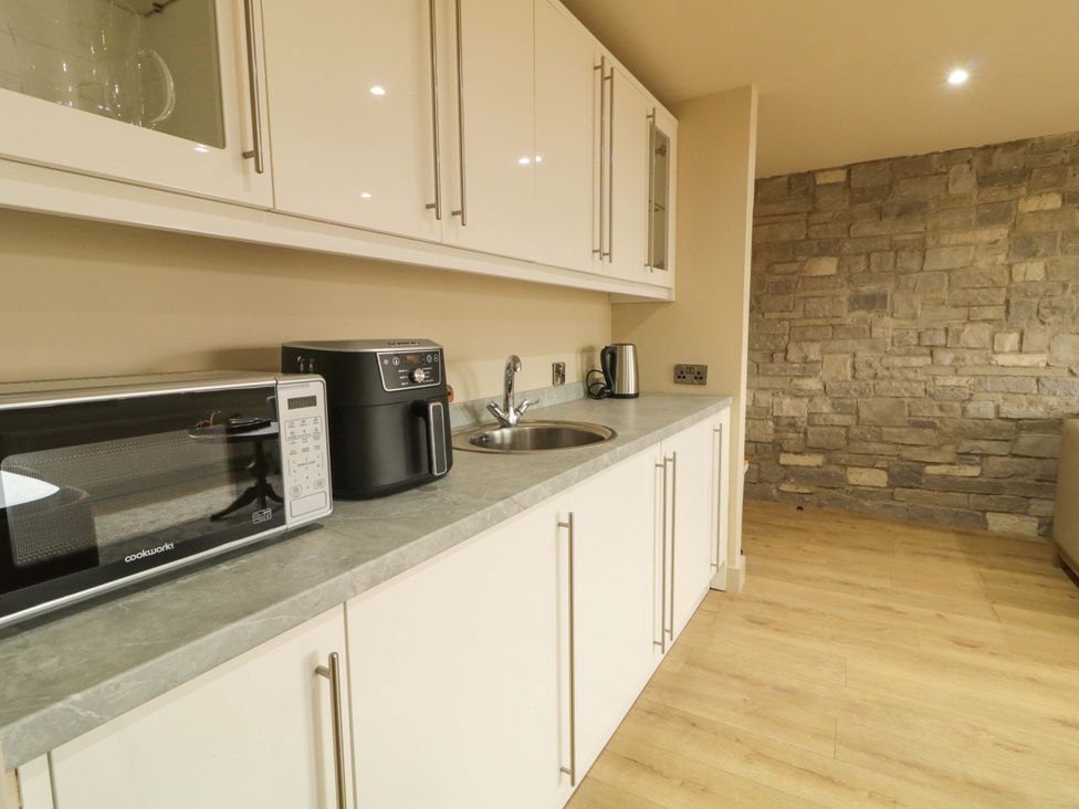 A kitchen with a microwave, air fryer, kettle, and sink at Apartment 1 Londonderry