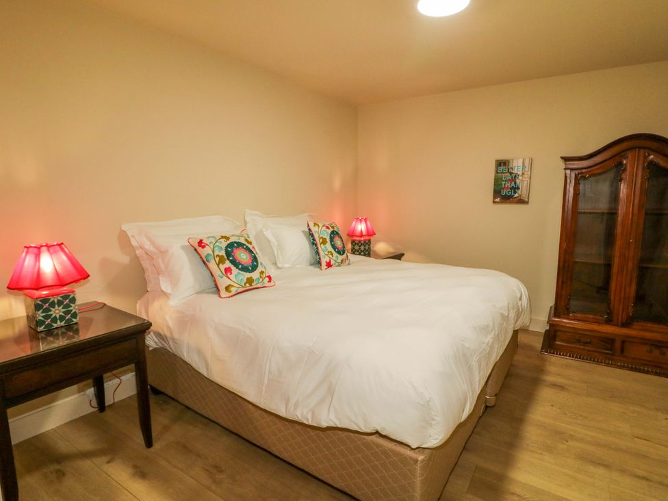 A bedroom with a bed, nightstand, lamp, and cabinet at Apartment 1 in Londonderry