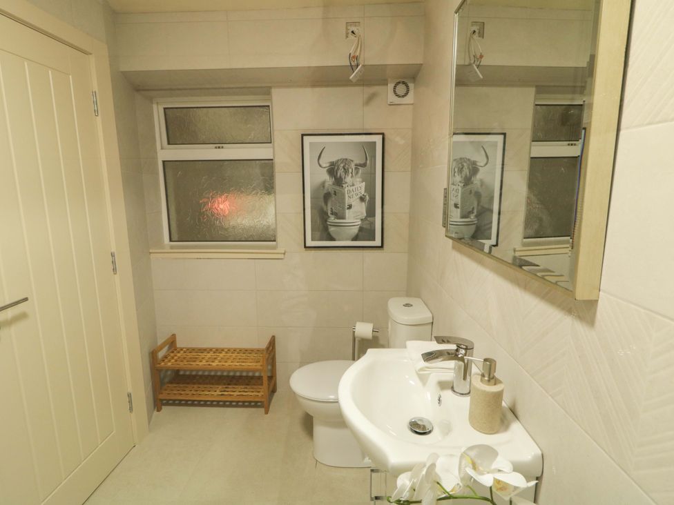 A bathroom with a toilet, sink, and wall art at Apartment 1 Londonderry