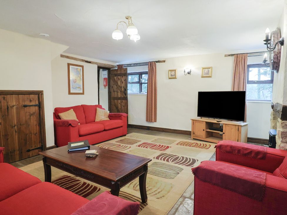 A living room with a television and red sofas at Cider House in Hawkchurch