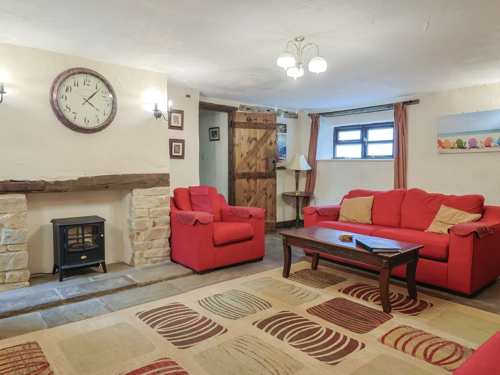 A living room with red sofas and a clock at Cider House in Hawkchurch