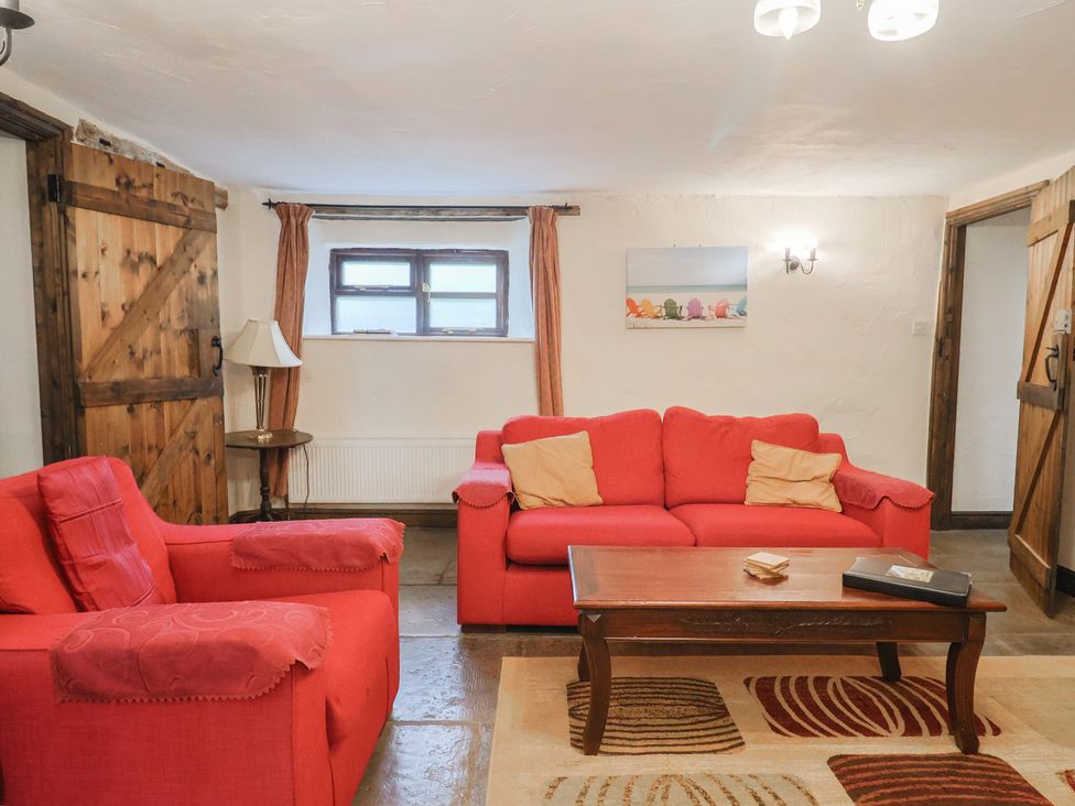 A living room with two red sofas and a coffee table at Cider House in Hawkchurch