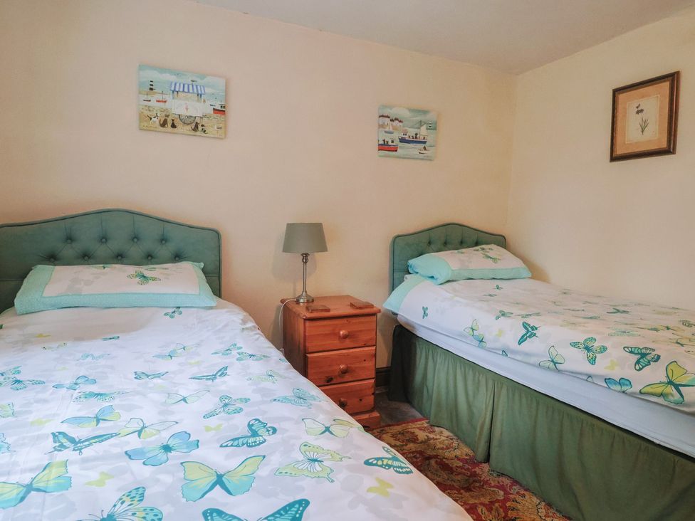 A bedroom with two beds and a nightstand at Cider House in Hawkchurch