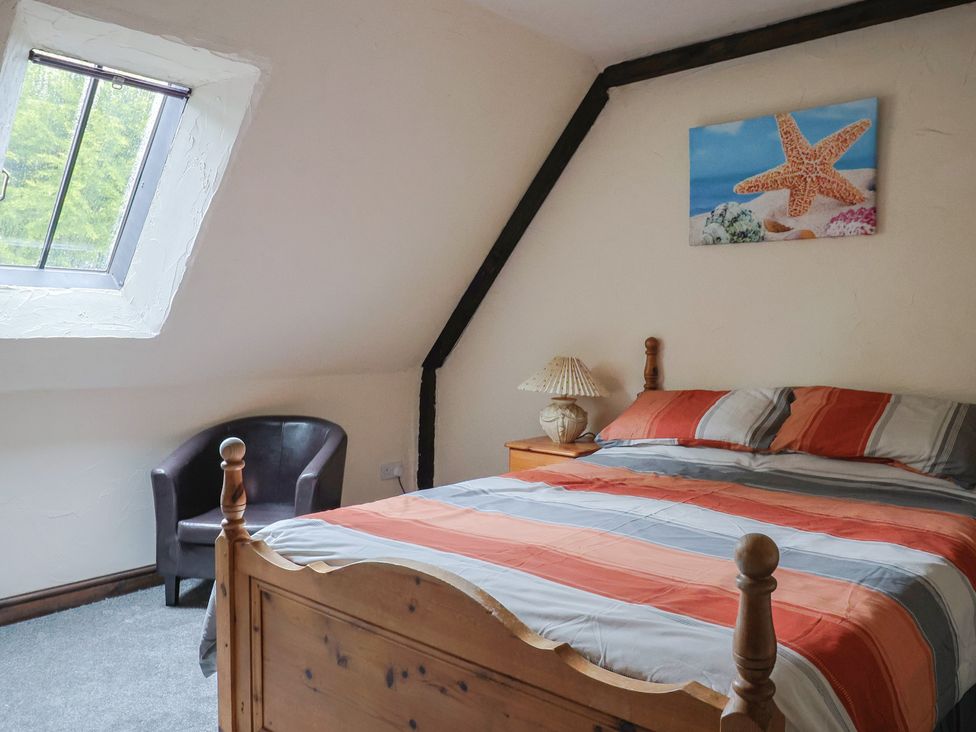 A bedroom with a bed and armchair at Cider House in Hawkchurch