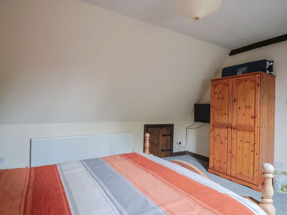 A bedroom with a bed and a wardrobe at Cider House in Hawkchurch