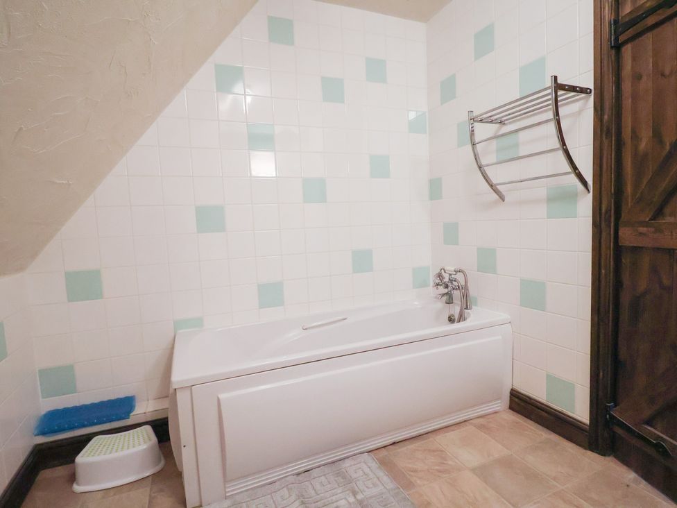 A bathroom with a bathtub and towel rack at Cider House in Hawkchurch
