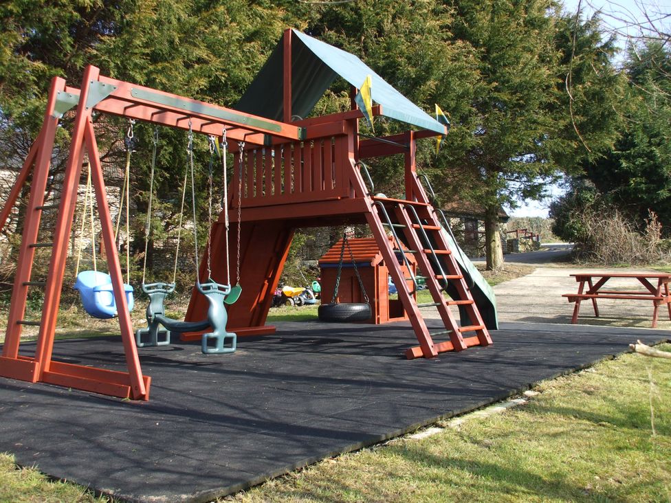 A playground with swings and a climbing frame at Cider House in Hawkchurch