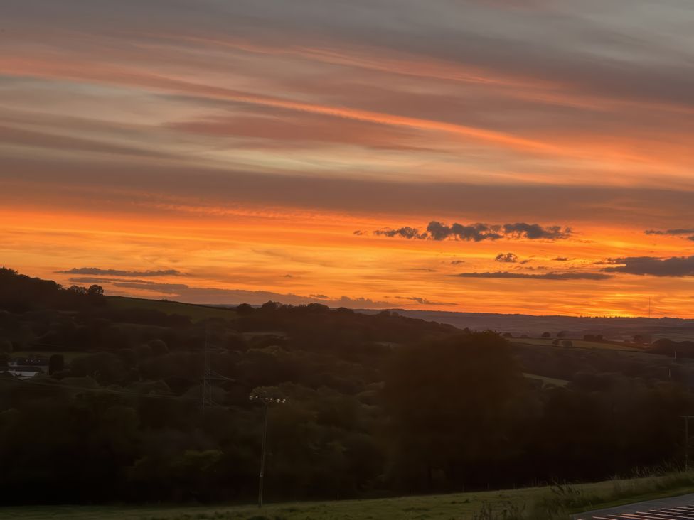 A sunset with clouds over hills and power lines at Cider House in Hawkchurch