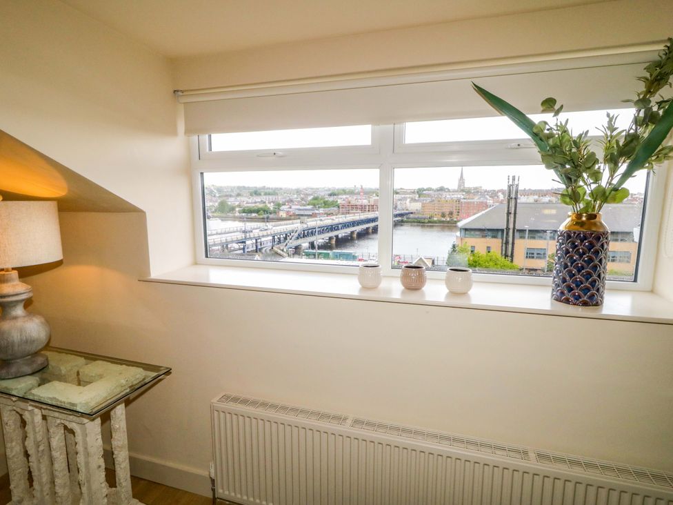 A living room with a lamp and window overlooking the river at Apartment 2 in Derry