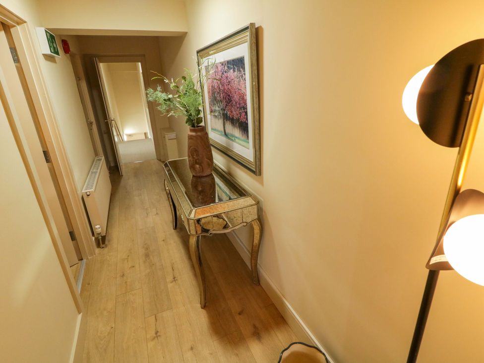 A hallway with a table, light, and picture at Apartment 2 in Derry