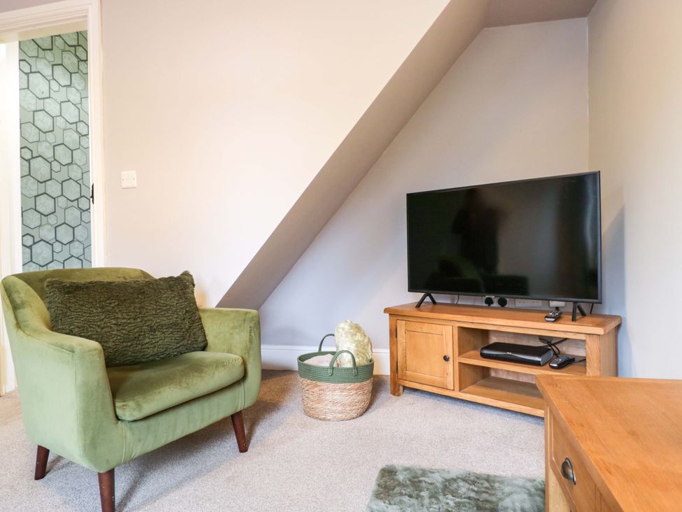 A living room with a green armchair and television at Tethera in Ennerdale