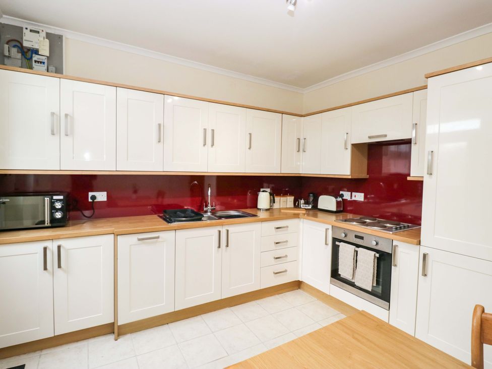 A kitchen with cabinets, microwave, sink, and oven at Tethera in Ennerdale
