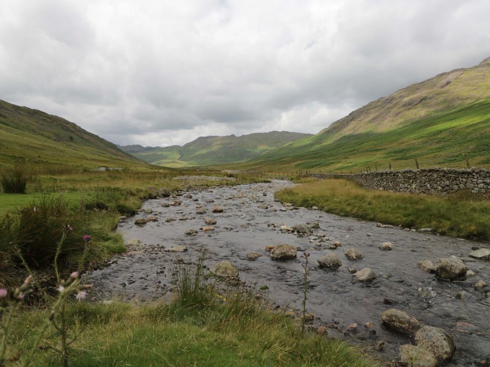 A river flowing through a valley surrounded by mountains at Tethera in Ennerdale