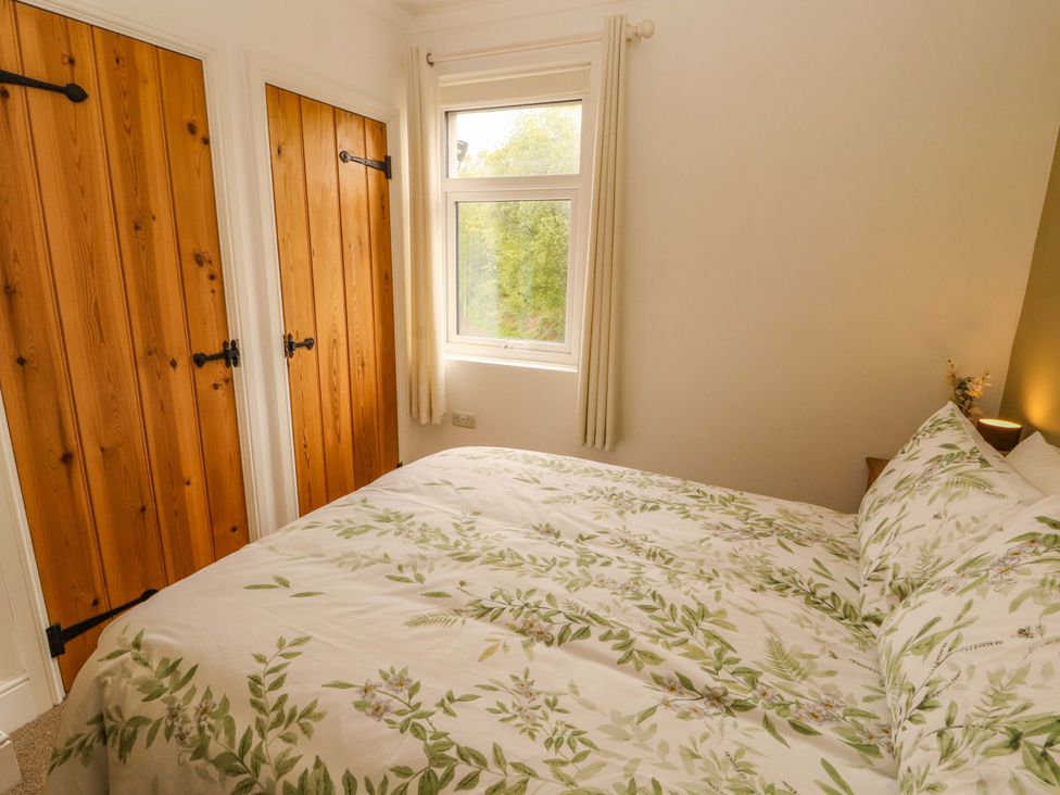 A bedroom with a bed and wooden wardrobe doors at Tethera in Ennerdale