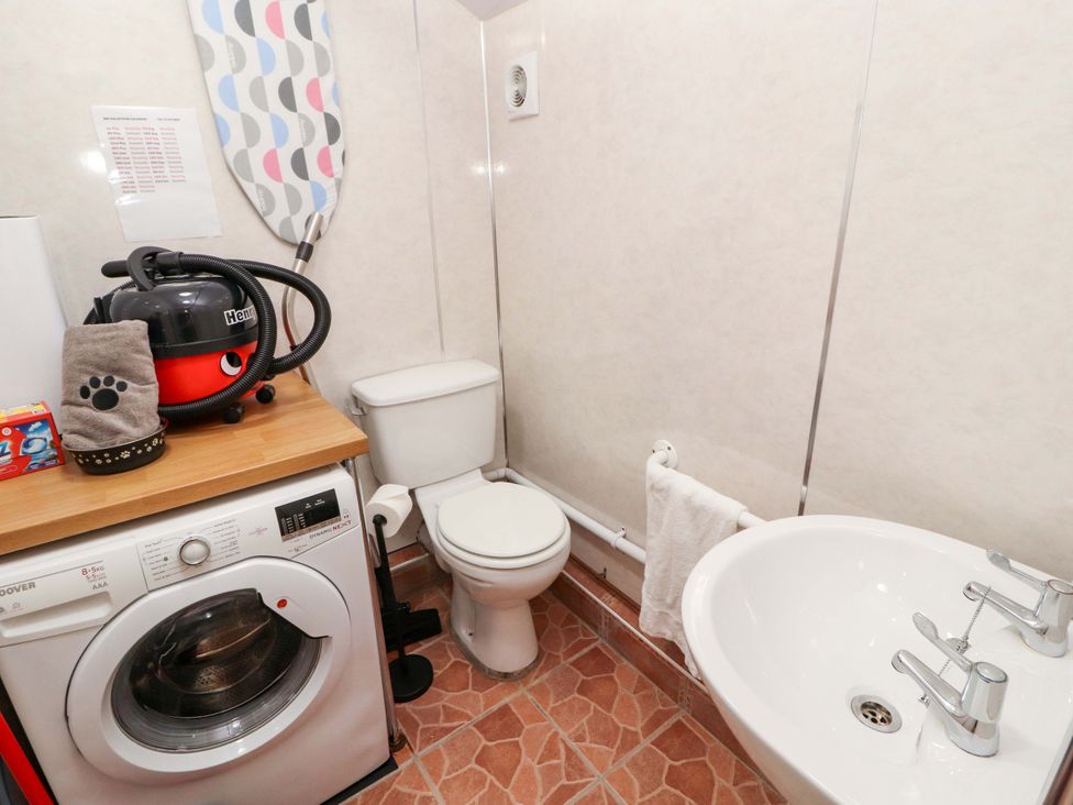 A bathroom with a washing machine, toilet, and sink at Tethera in Ennerdale