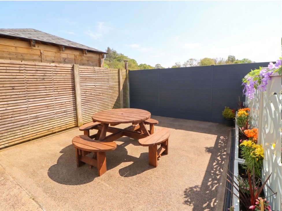 A garden with a wooden table and benches at Tethera in Ennerdale
