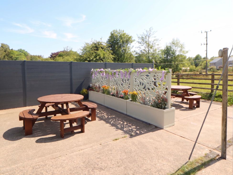 An outdoor seating area with tables and flowers at Tethera in Ennerdale