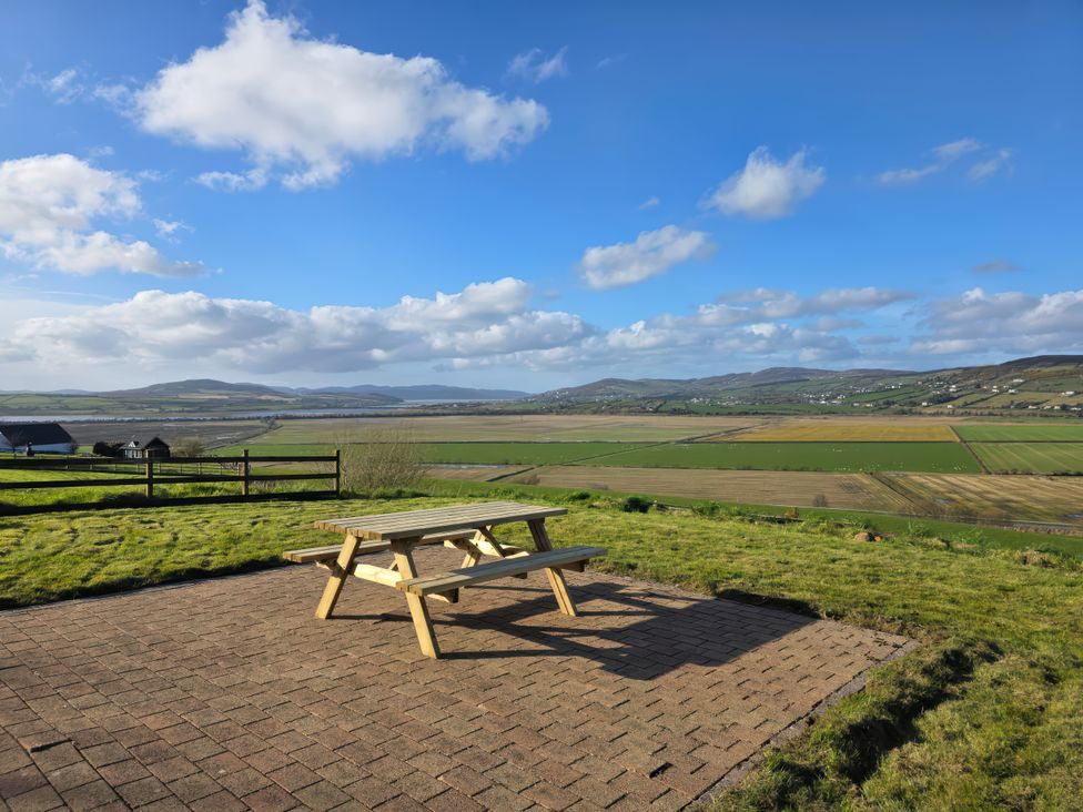 A picnic table on a patio with a view of fields and hills at An Grianan Getaway in Burt