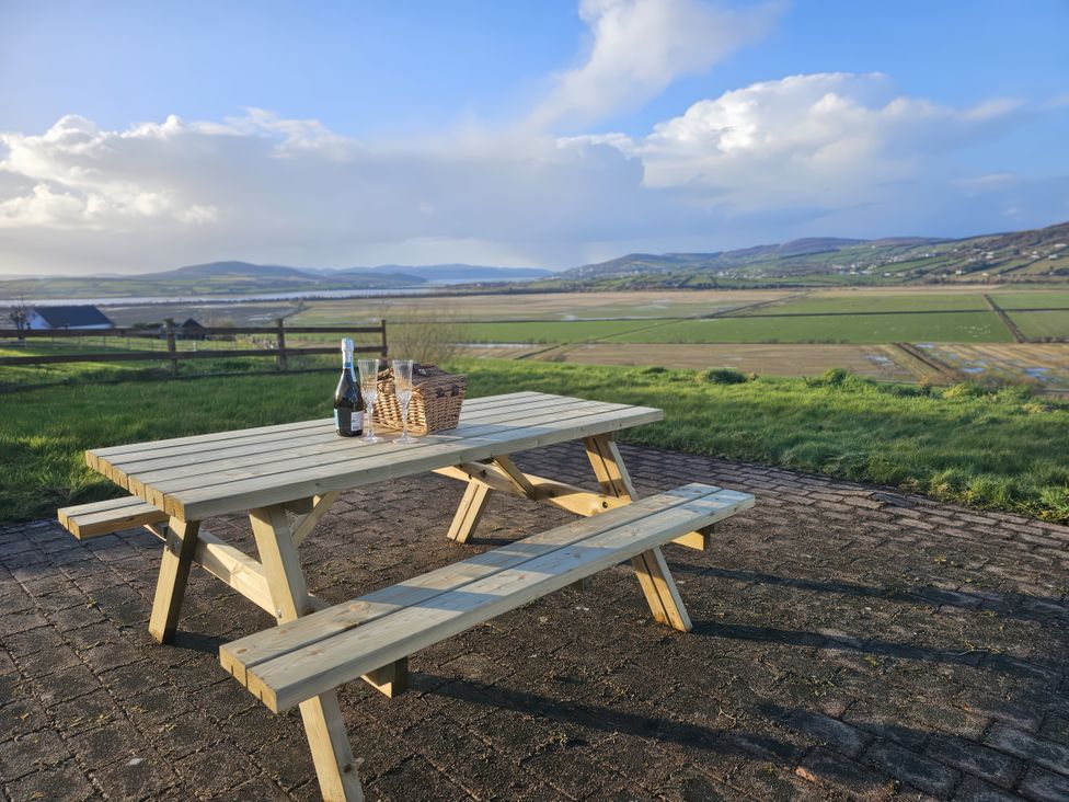 A picnic table with a bottle and basket at An Grianan Getaway in Burt