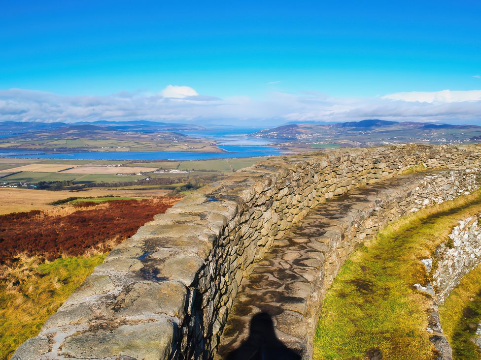 A view from a stone wall overlooking hills and a river at An Grianan Getaway in Burt